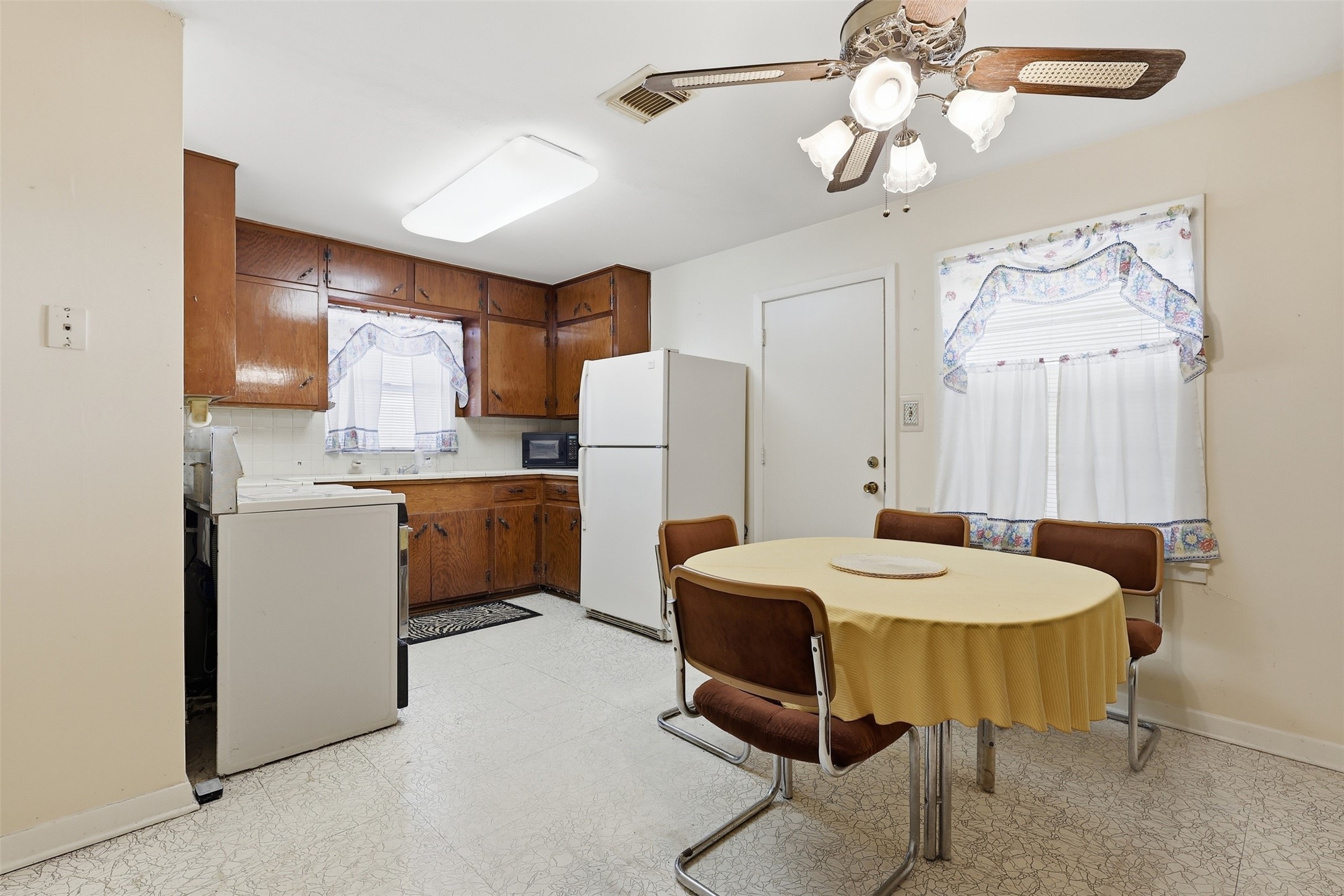 5707 Waltrip Street Houston, TX 77087 - Photo 7 of 15 This cozy kitchen features a classic dining area and a ceiling fan. The space is brightened by natural light from curtained windows, offering a warm, inviting atmosphere.