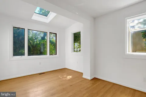 an empty room with wooden floor chandelier and windows
