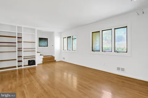 a view of an empty room with window and wooden floor