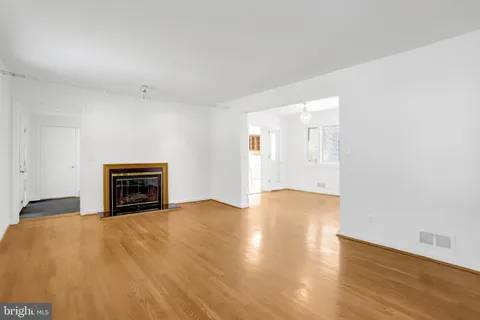 a view of an empty room with wooden floor fireplace and a window