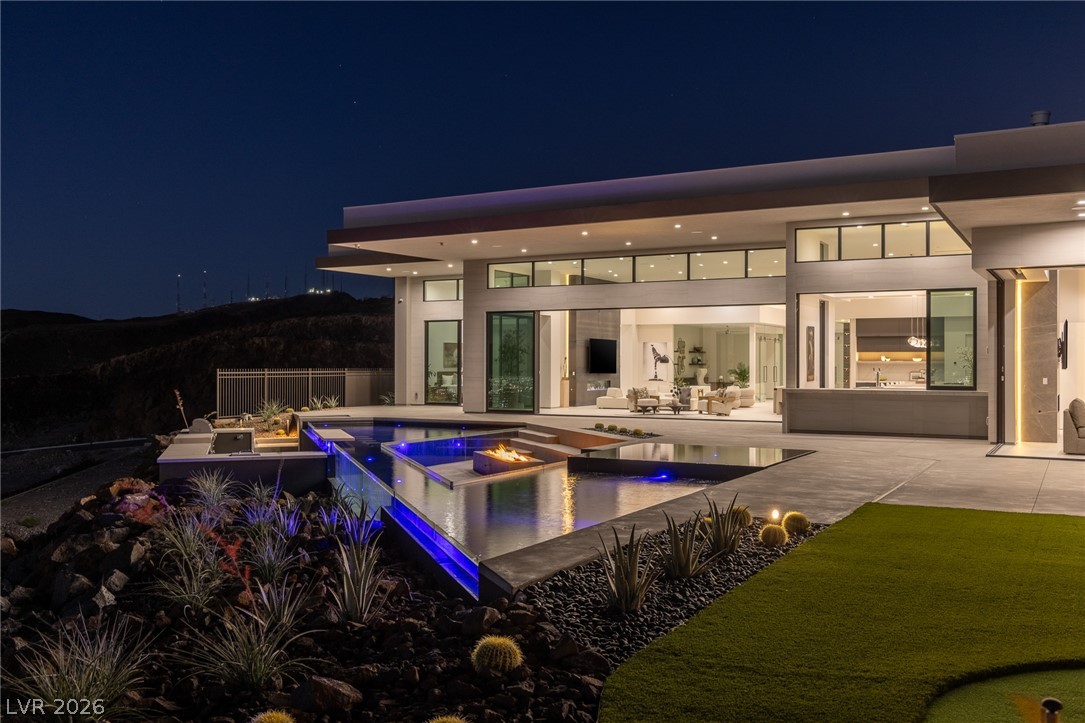 563 Grand Rim Drive Henderson, NV 89012 - Photo 54 of 70 An illuminated modern residence offers a captivating pool with a fire feature and expansive views.