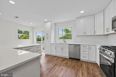 a kitchen with stainless steel appliances white cabinets and wooden floors