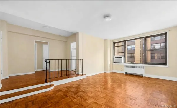 a view of an empty room with window and wooden floor