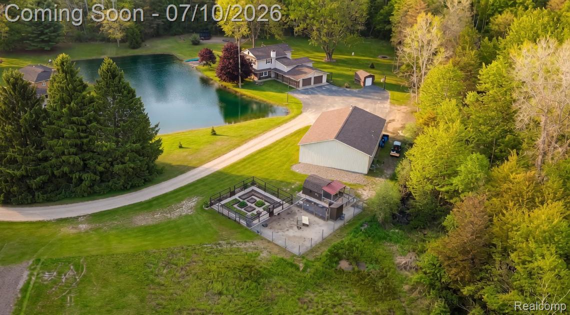 5278 Skelton Road Columbiaville, MI 48421 - Photo 16 of 64 Expansive property featuring a tranquil pond, gravel driveway, detached garage with multiple bays, additional outbuilding, and fenced garden beds