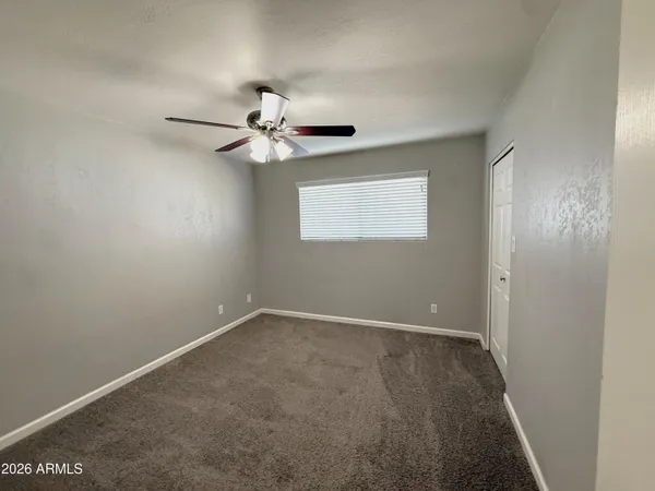 an empty room with a window and a fan