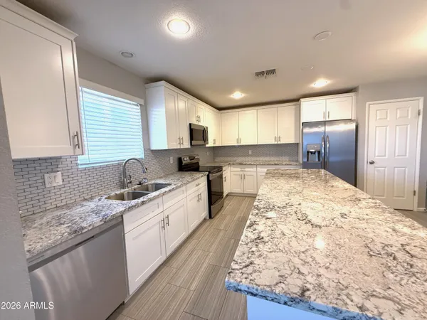 a large kitchen with kitchen island granite countertop a sink stove refrigerator and cabinets
