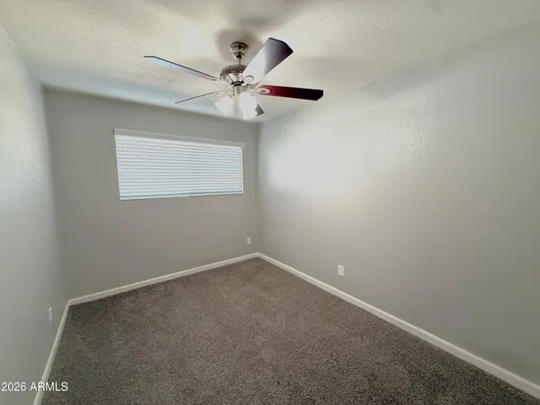 an empty room with a window and a fan