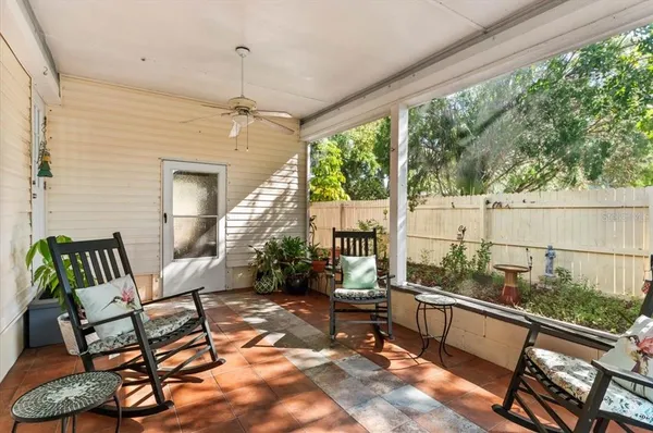 a balcony with couple of chairs and a potted plant