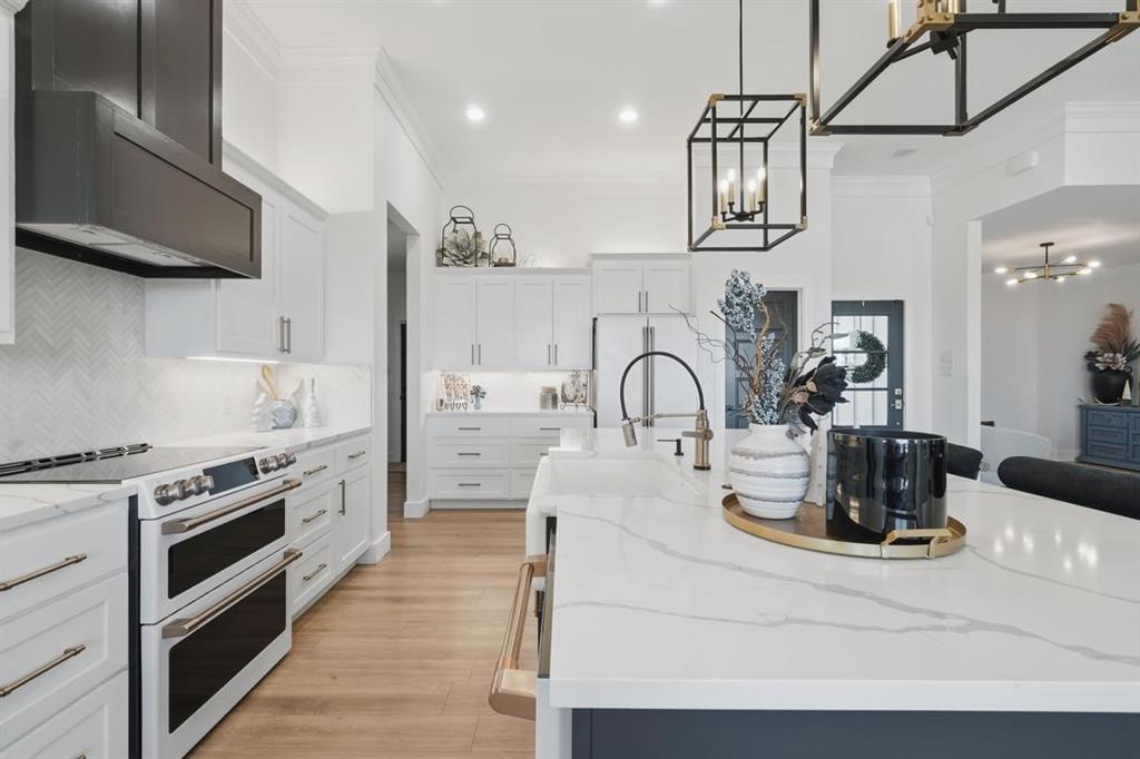 136 Mistletoe Ridge Lawn, TX 79530 - Photo 13 of 37 Kitchen featuring range with two ovens, light stone counters, white cabinets, light wood finished floors, and crown molding