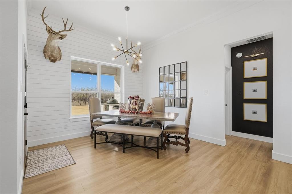 136 Mistletoe Ridge Lawn, TX 79530 - Photo 14 of 37 Dining space with light wood-style floors, a chandelier, wood walls, and ornamental molding