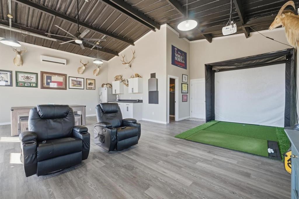 136 Mistletoe Ridge Lawn, TX 79530 - Photo 30 of 37 Recreation room with golf simulator, high vaulted ceiling, light wood-style flooring, a wall unit AC, and ceiling fan