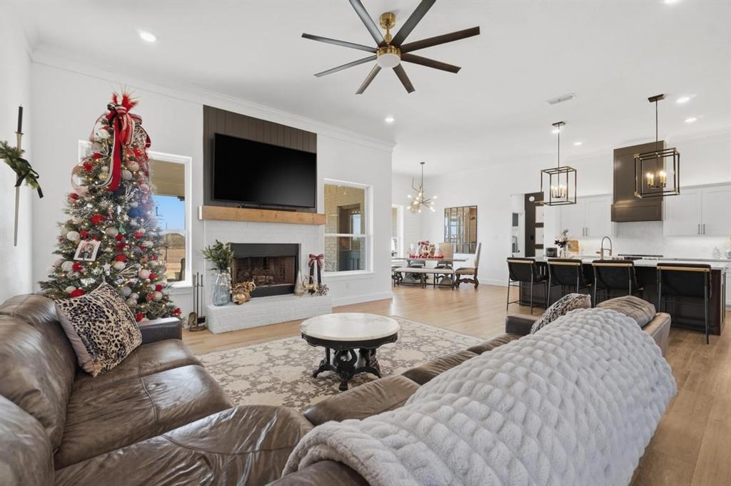 136 Mistletoe Ridge Lawn, TX 79530 - Photo 7 of 37 Living area featuring light wood finished floors, a ceiling fan, a brick fireplace, and crown molding