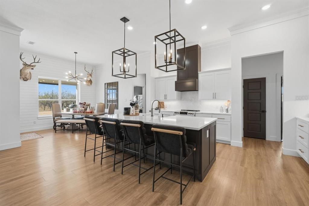 136 Mistletoe Ridge Lawn, TX 79530 - Photo 10 of 37 Kitchen with a breakfast bar area, white cabinetry, a center island with sink, crown molding, and pendant lighting