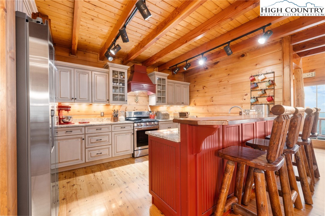 635 Acorn Road Zionville, NC 28698 - Photo 15 of 50 a kitchen with stainless steel appliances kitchen island granite countertop a table chairs and wooden cabinets