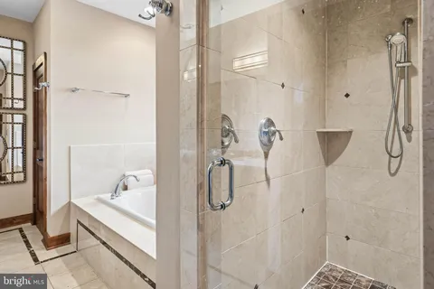 a bathroom with a tub a mirror and a shower