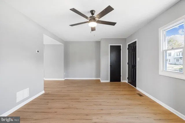 a view of an empty room with window and wooden floor