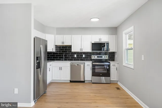 a kitchen with stainless steel appliances a stove a microwave and white cabinets