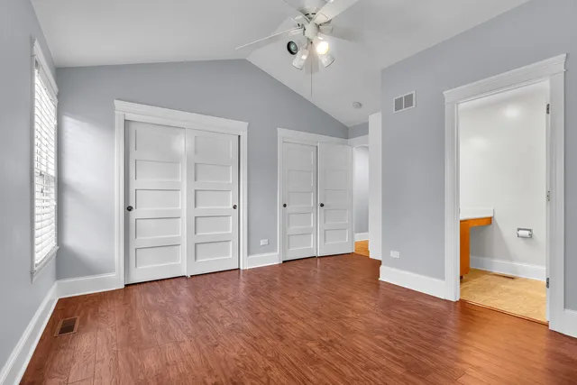 an empty room with wooden floor cabinet and windows