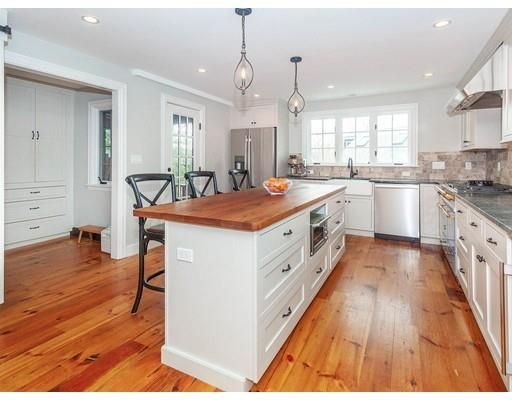 a large kitchen with kitchen island a stove a sink dishwasher and a dining table with wooden floor