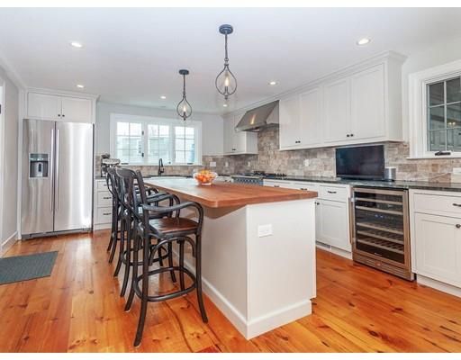 a kitchen with stainless steel appliances a dining table chairs stove and cabinets