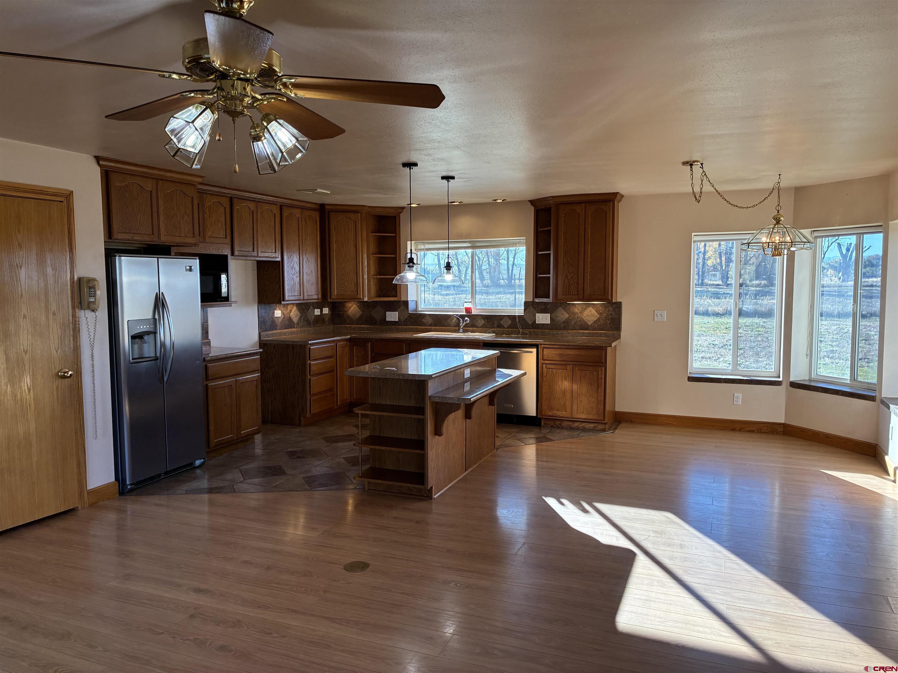 15334 County Rd T.5 La Jara, CO 81140 - Photo 12 of 28 a kitchen with stainless steel appliances granite countertop a refrigerator a sink dishwasher a stove and a dining table with wooden floor