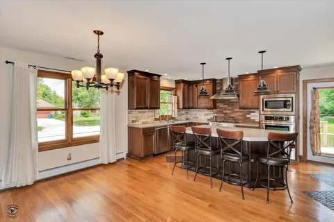 a kitchen with stainless steel appliances a refrigerator a stove a sink dishwasher and white cabinets with wooden floor