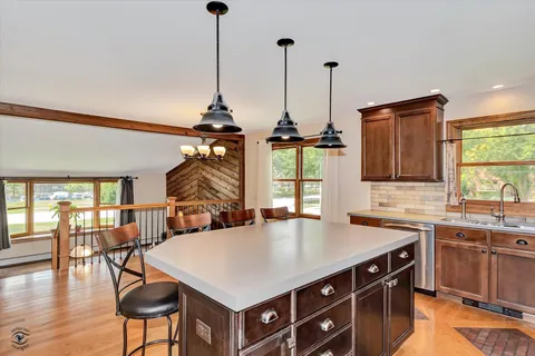 a kitchen with stainless steel appliances granite countertop a sink a stove and chairs