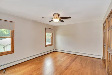 a view of empty room with wooden floor and fan
