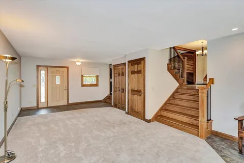 a view of an empty room with wooden floor and stairs