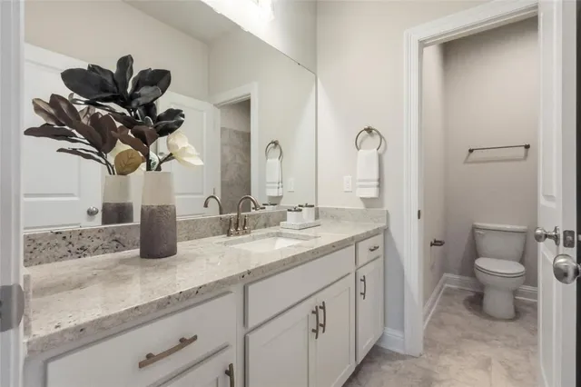 a bathroom with a granite countertop sink a toilet and a mirror