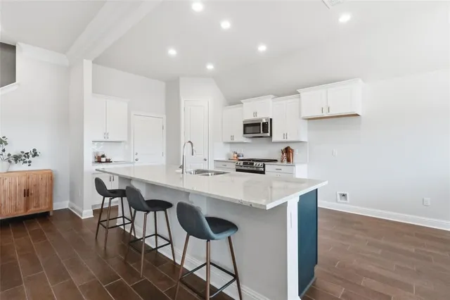 a kitchen with a sink a stove a refrigerator and white cabinets with wooden floor