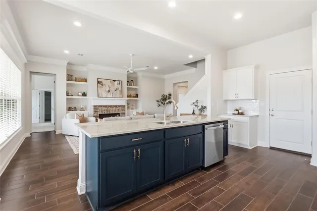 a large kitchen with stainless steel appliances a sink dishwasher stove and white cabinets with wooden floor