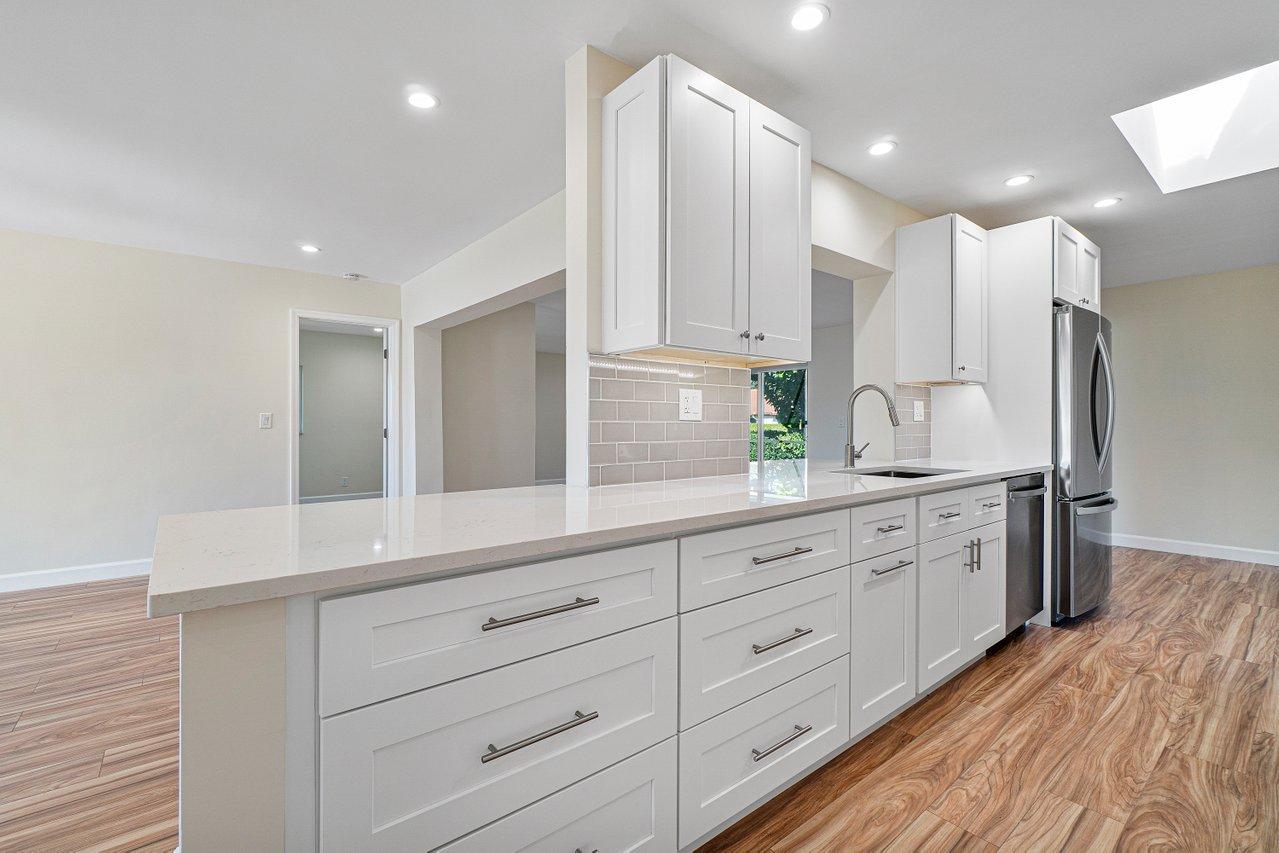 6359 Winding Brook Way Delray Beach, FL 33484 - Photo 7 of 24 a large white kitchen with stainless steel appliances and white cabinets