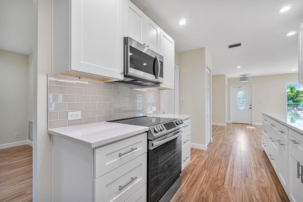 6359 Winding Brook Way Delray Beach, FL 33484 - Photo 8 of 24 a kitchen with stainless steel appliances a stove microwave and sink