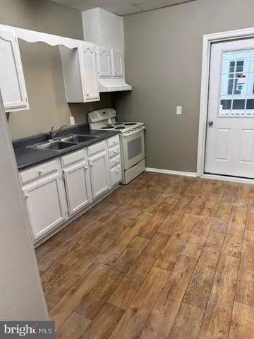 a kitchen with granite countertop a sink a stove and cabinets