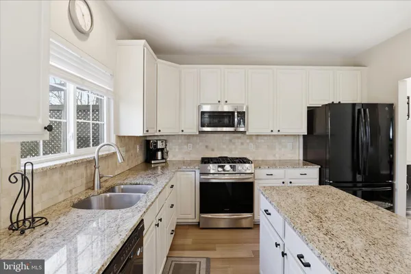 a kitchen with granite countertop a refrigerator stove and sink