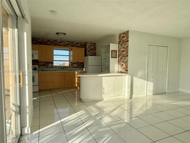 a view of a kitchen with kitchen island granite countertop a refrigerator and a stove top oven