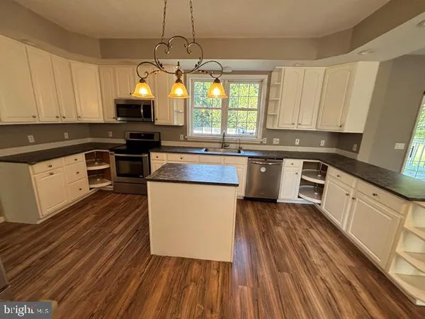 a kitchen with kitchen island granite countertop wooden floors stainless steel appliances and sink