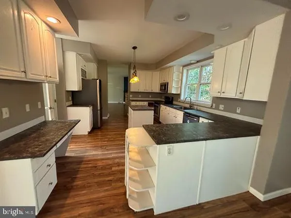 a kitchen with granite countertop a sink a counter top space and cabinets