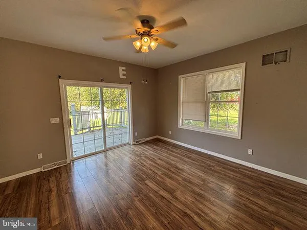 a view of an empty room with a window and wooden floor