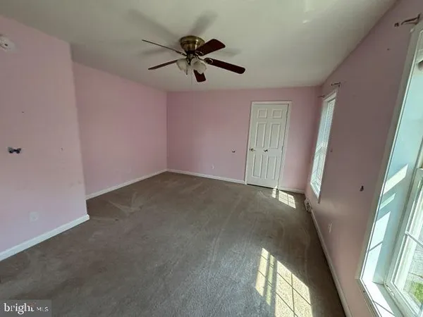 an empty room with windows and fan view