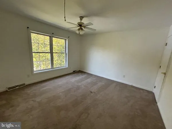 an empty room with a ceiling fan and window