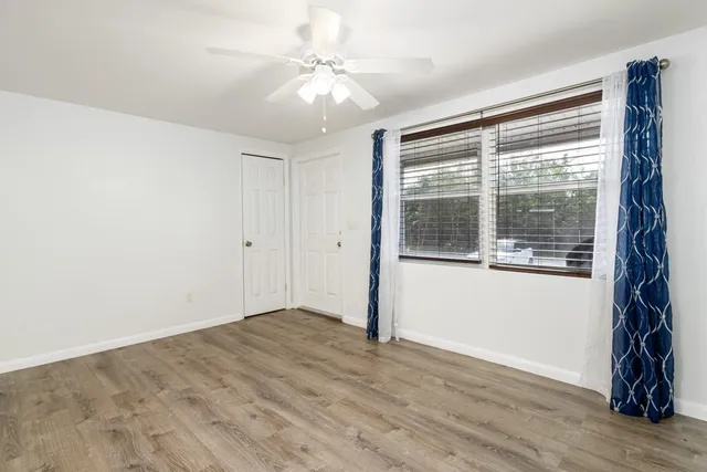 a view of an empty room with wooden floor and a window