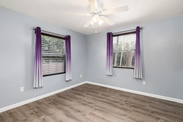 a view of an empty room with a window and wooden floor