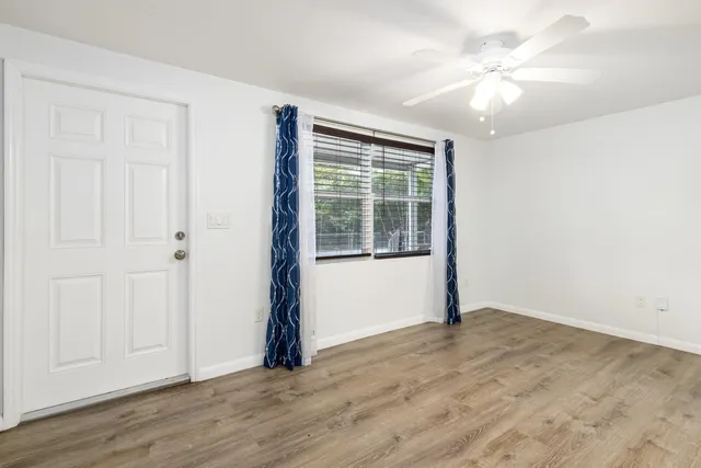 an empty room with wooden floor and windows