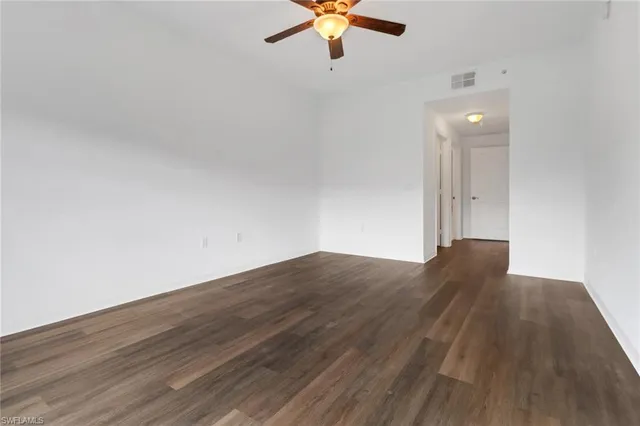 an empty room with wooden floor fan and window