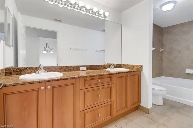 a bathroom with a granite countertop sink a toilet mirror and bathtub
