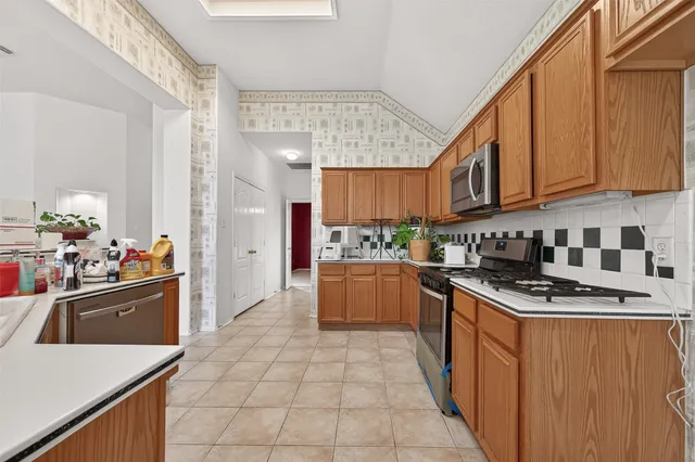 a kitchen with stainless steel appliances granite countertop a stove top oven a sink dishwasher and cabinets with wooden floor