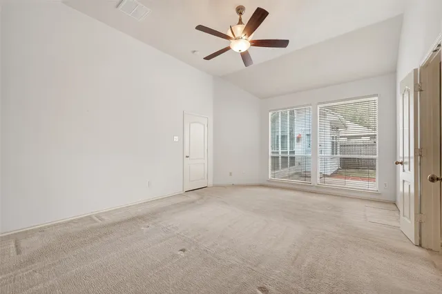 an empty room with windows and ceiling fan