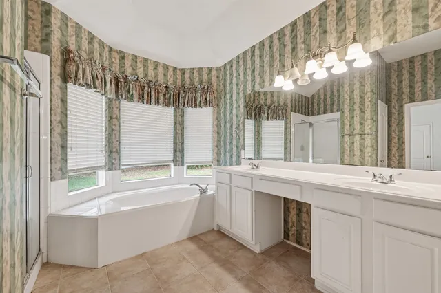 a spacious bathroom with a tub sink and mirror